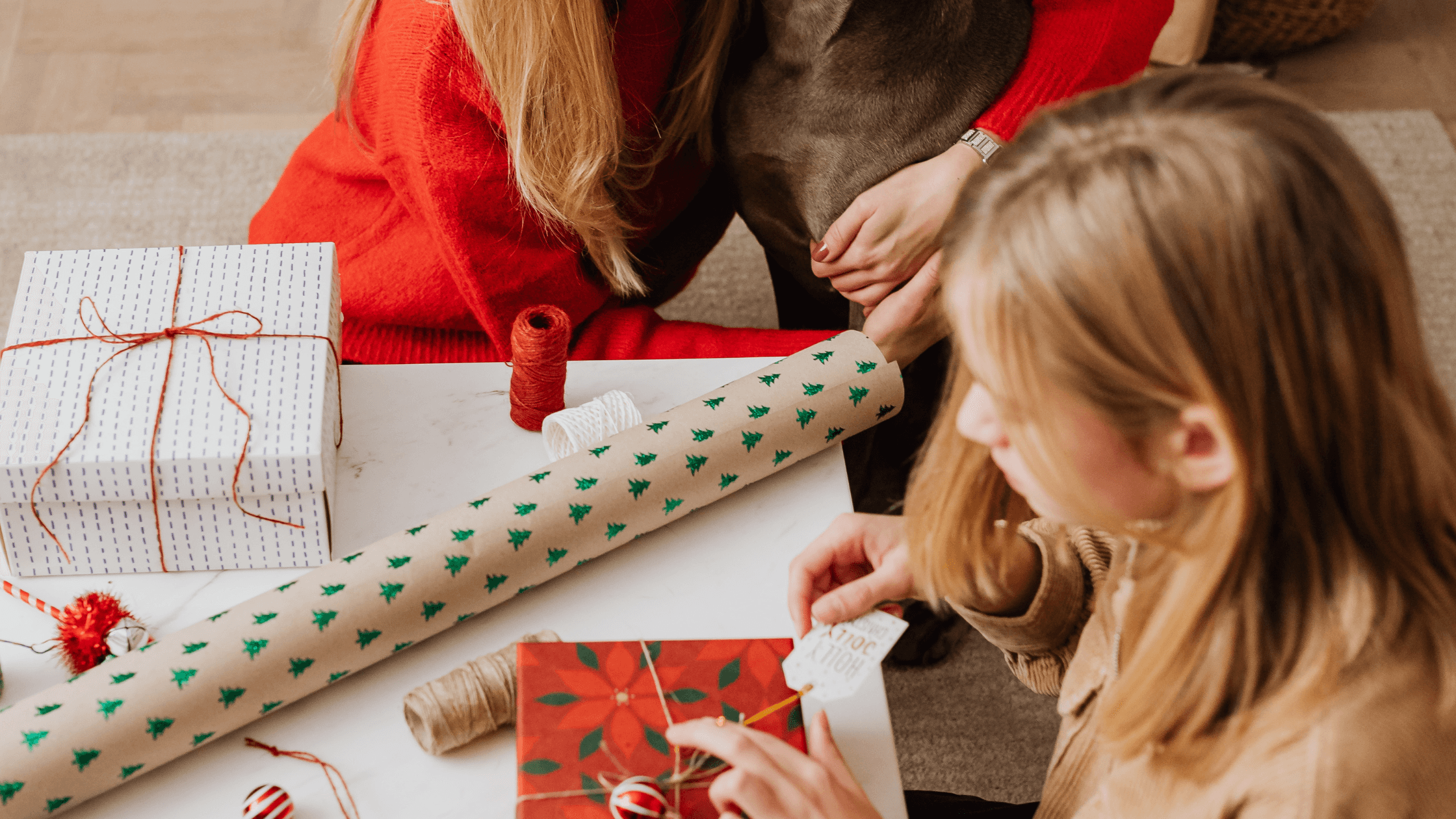 anyuka és kislánya közösen csomagolnak karácsonyi csomagolópapírba ajándékokat