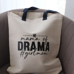 Natúr színű pamut vászontáska „mama of DRAMA #girlmom” felirattal, barna fotelben elhelyezve.