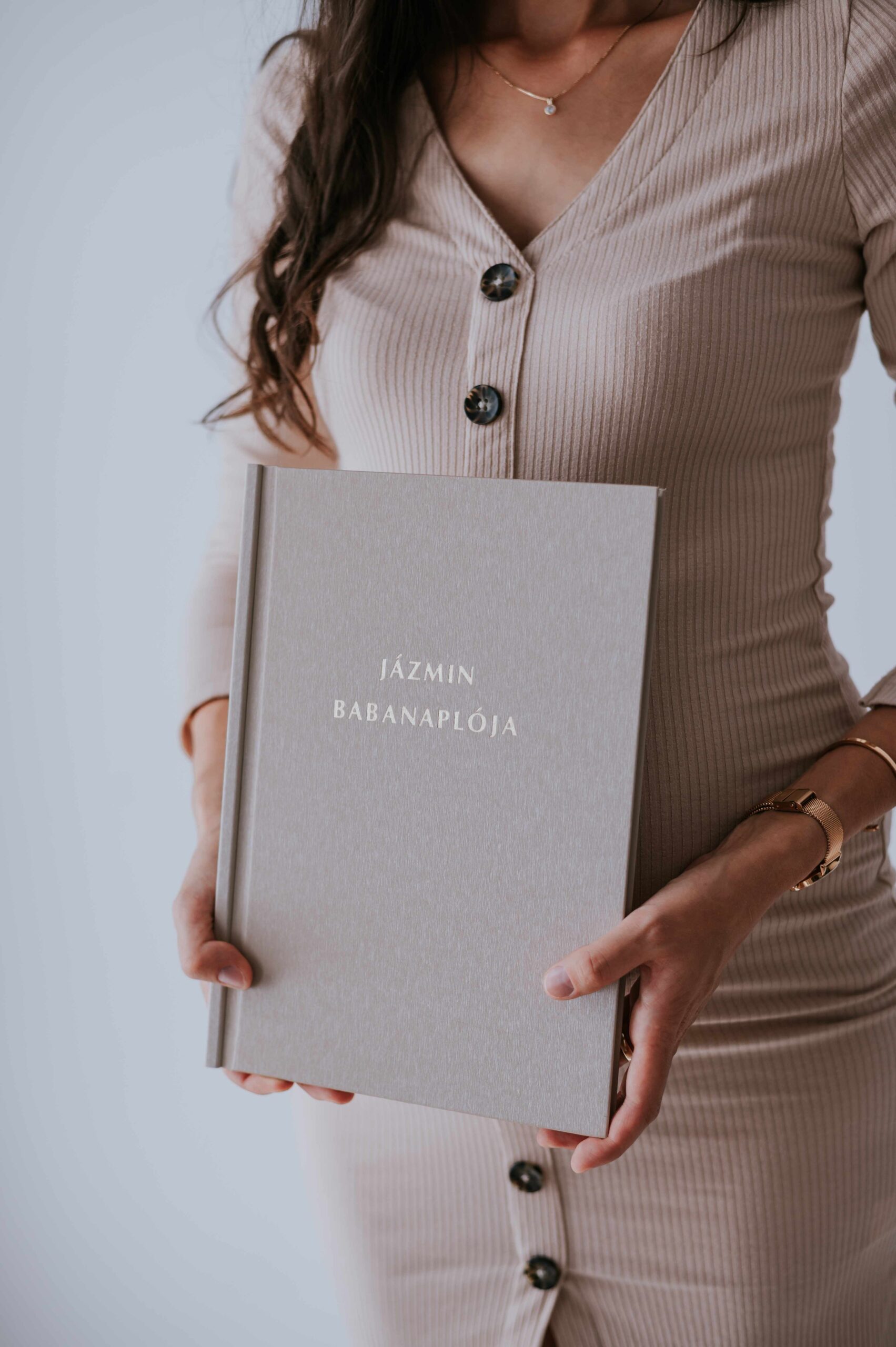 niMin névre szóló babanapló bézs színben kézben tartva