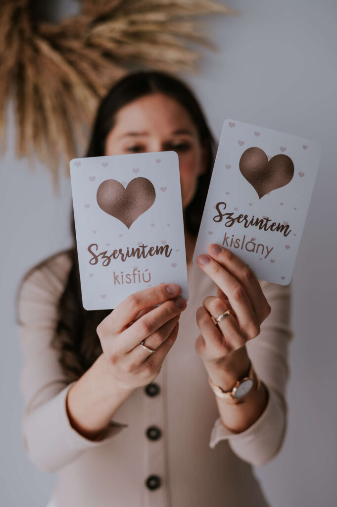 niMin várandós mérföldkőkártya szerintem kislány, szerintem kisfiú felirattal, kézben tartva
